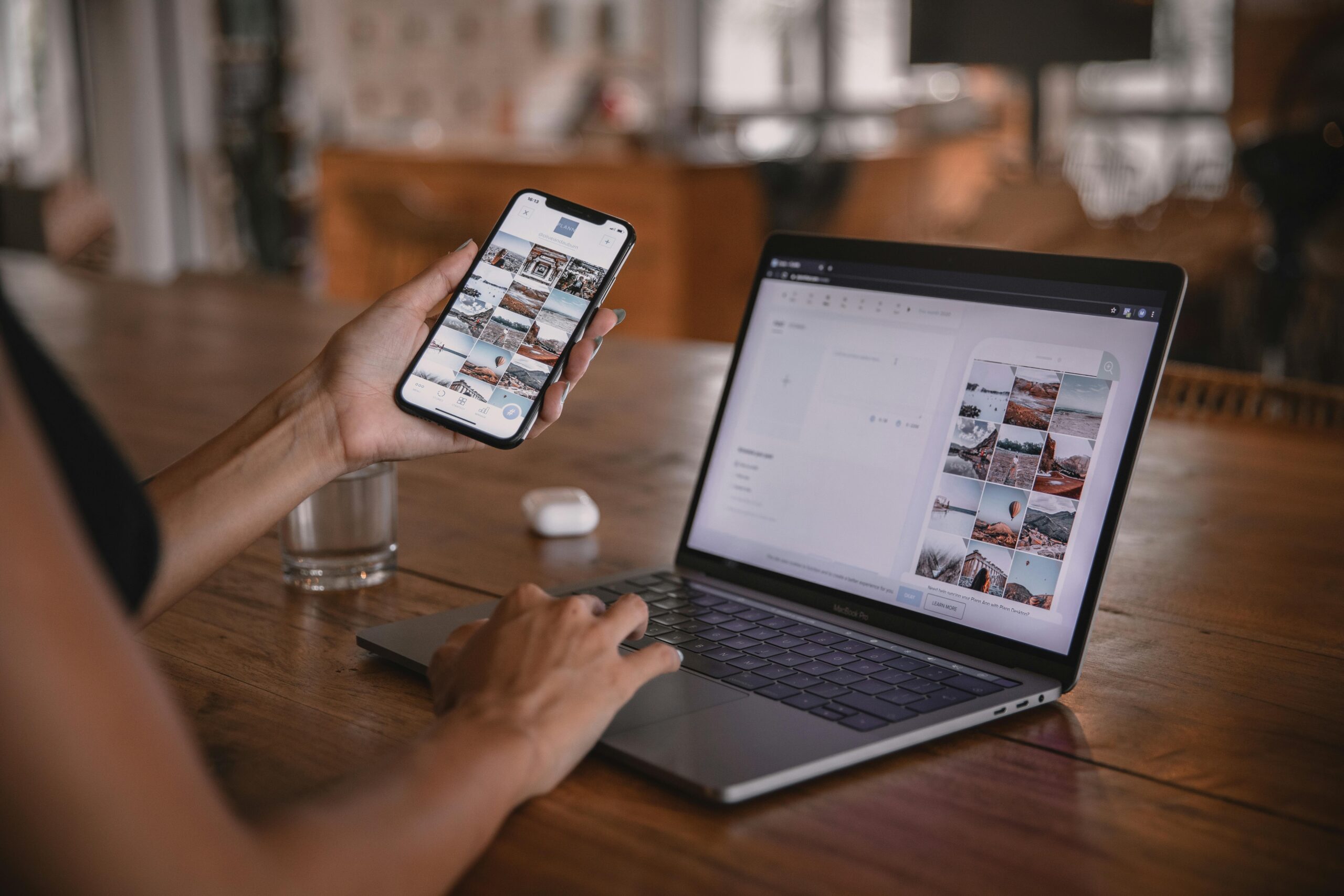 A woman looking at a laptop and phone, both showing social media.